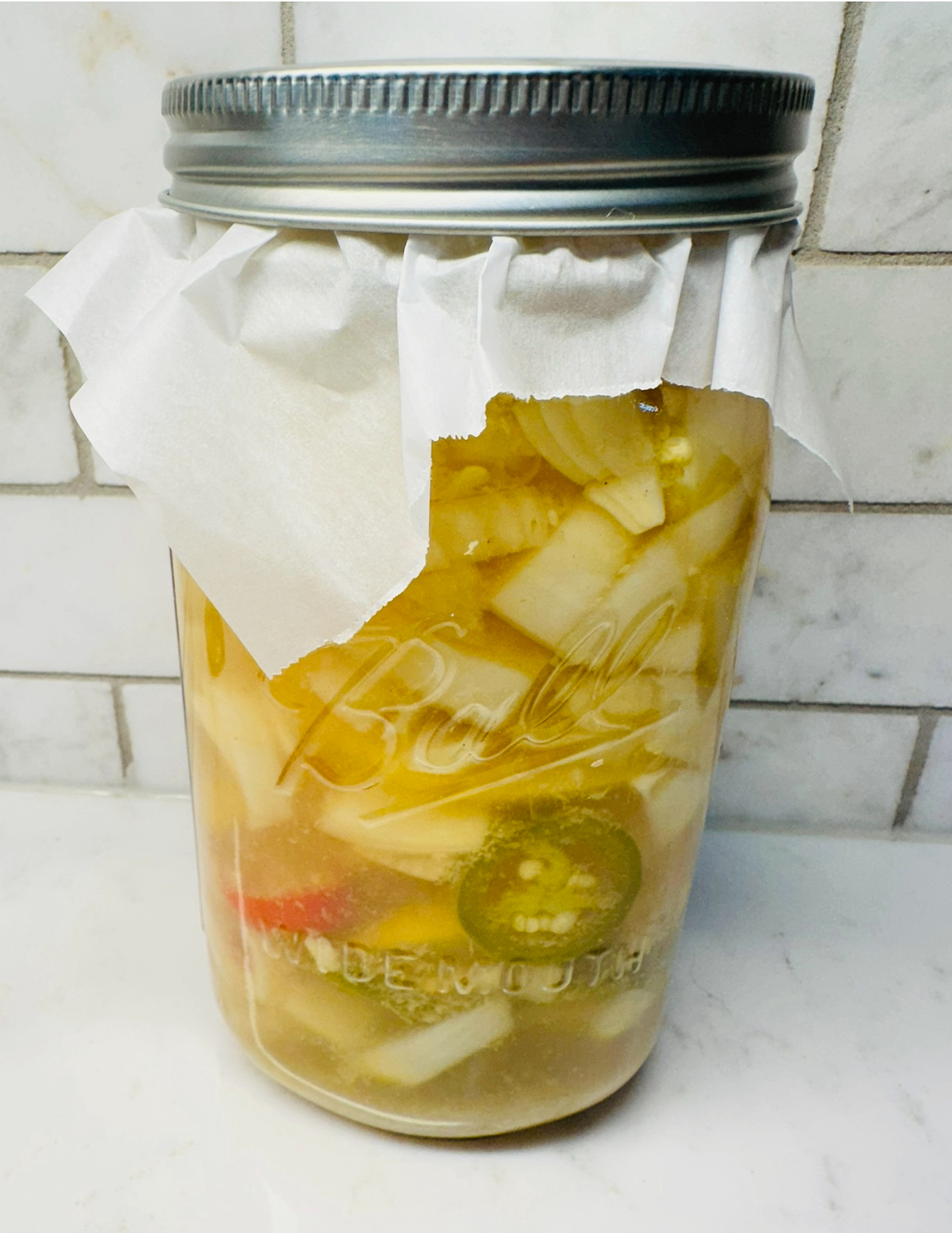 Homemade fire cider ingredients including apple cider vinegar, garlic, ginger, onions, and hot peppers on a wooden table, showcasing the health benefits of this traditional herbal remedy."