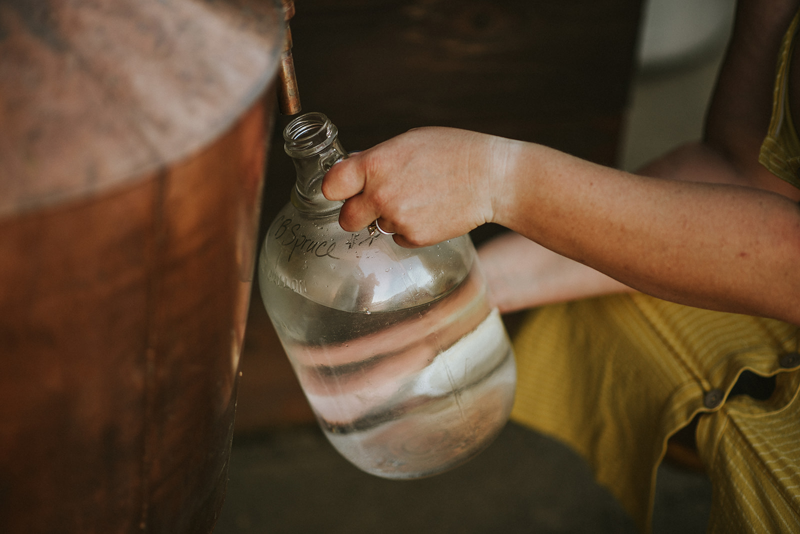 a women draws hydrosol from a copper still